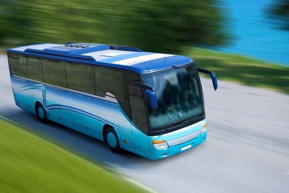 A blue bus driving in a country road